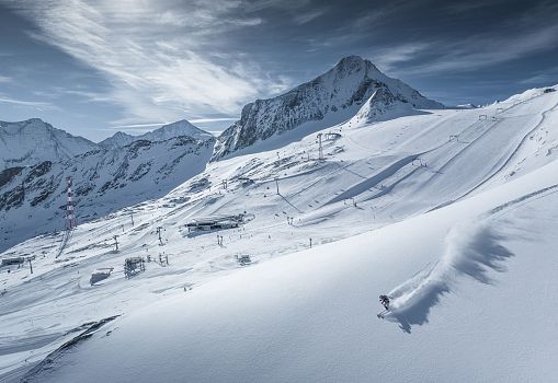 Ein Skifahrer fährt durch frischen Pulverschnee in einer verschneiten Gletscherlandschaft.