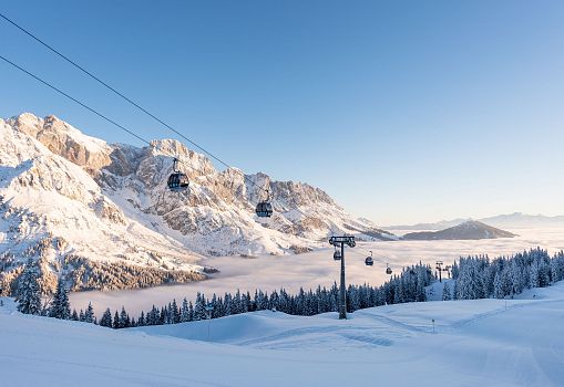 Cable cars gliding over a snowy winter landscape with a stunning mountain backdrop.
