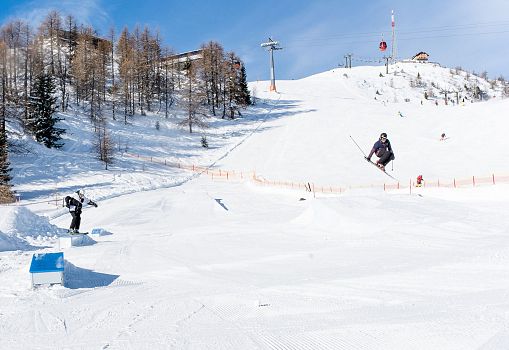 Two skiers jumping and riding in the fun park on a sunny day