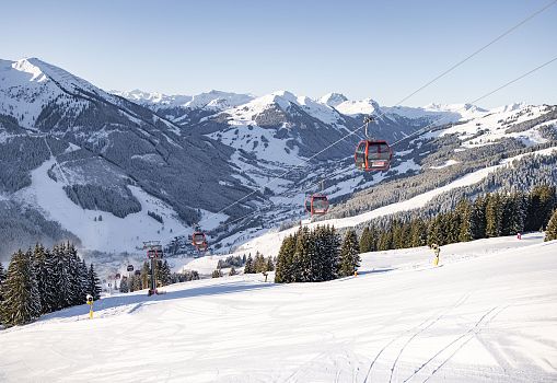 Cable cars floating above a snowy mountain landscape in bright sunlight.