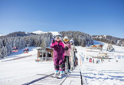 Children skiing on a conveyor lift in the Schatzberg Kinderland ski area.