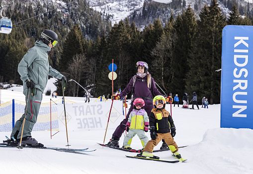 A family skiing together on a Kidsrun in a ski resort.