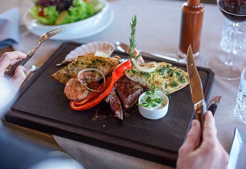 Ein Steakgericht mit Beilagen wird auf einem Holzbrett serviert.
