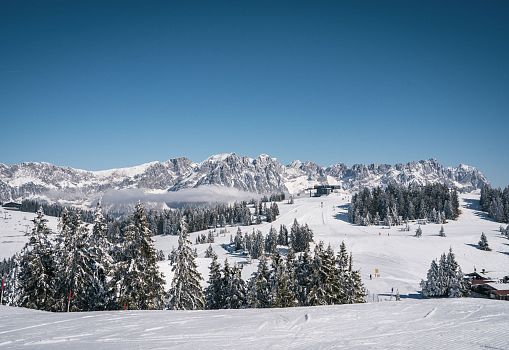 Verschneites Skigebiet mit breiten Pisten und beeindruckendem Bergpanorama.