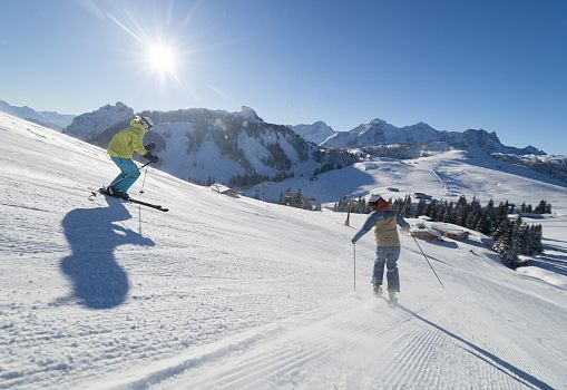 Two skiers are skiing down a freshly groomed slope in Almenwelt Lofer.