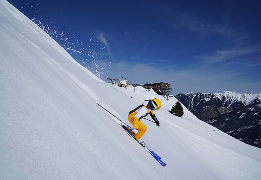A skier in yellow gear rides a steep slope at Riesneralm.