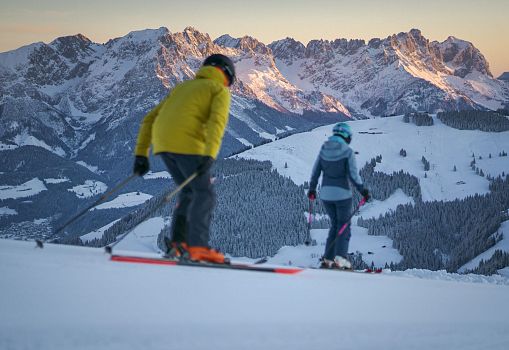 Zwei Skifahrer genießen den Ausblick auf verschneite Berge bei Sonnenaufgang
