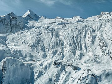 Aerial view of a snow-covered glacier ski resort surrounded by an impressive high alpine landscape.