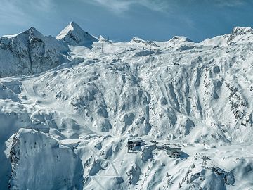 Luftaufnahme eines verschneiten Gletscherskigebiets mit beeindruckender Hochgebirgslandschaft.