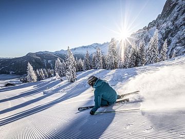A skier carves through powder snow in the sunshine at Dachstein West.